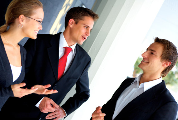 two men in suits and lady in suit smiling and talking